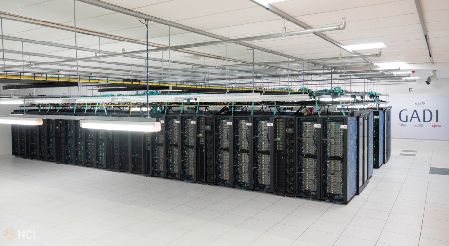 Wide picture of many rows of computer servers in a big open room, with blue artwork on one face.