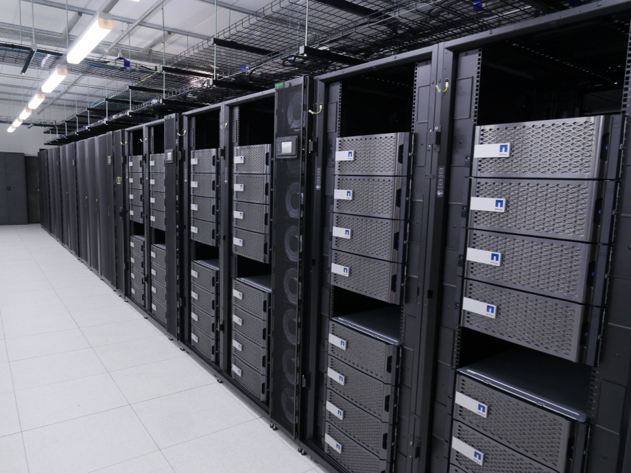 A long vertical stack filled with new grey and blue computer equipment extends to the back of the room.