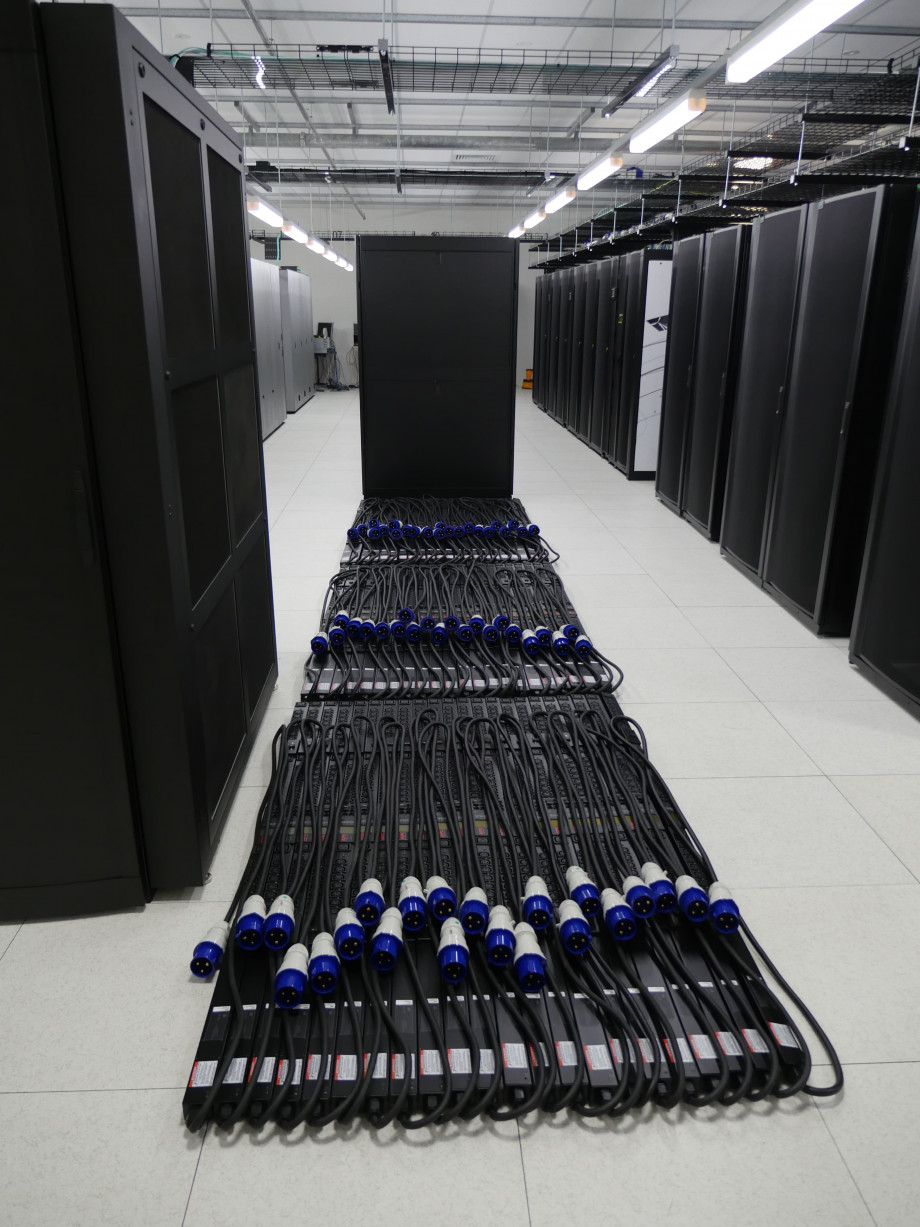 Neatly coiled thick black power cables with blue plugs lie on the floor ready for use.