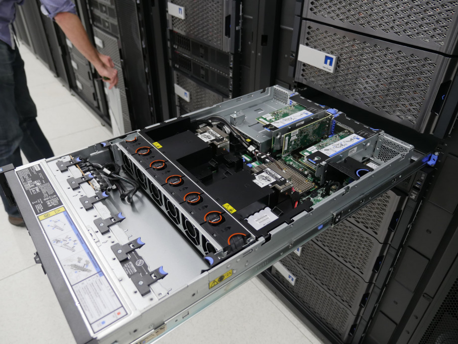 The inside of a computer server showing cabling, green motherboards and cooling units.