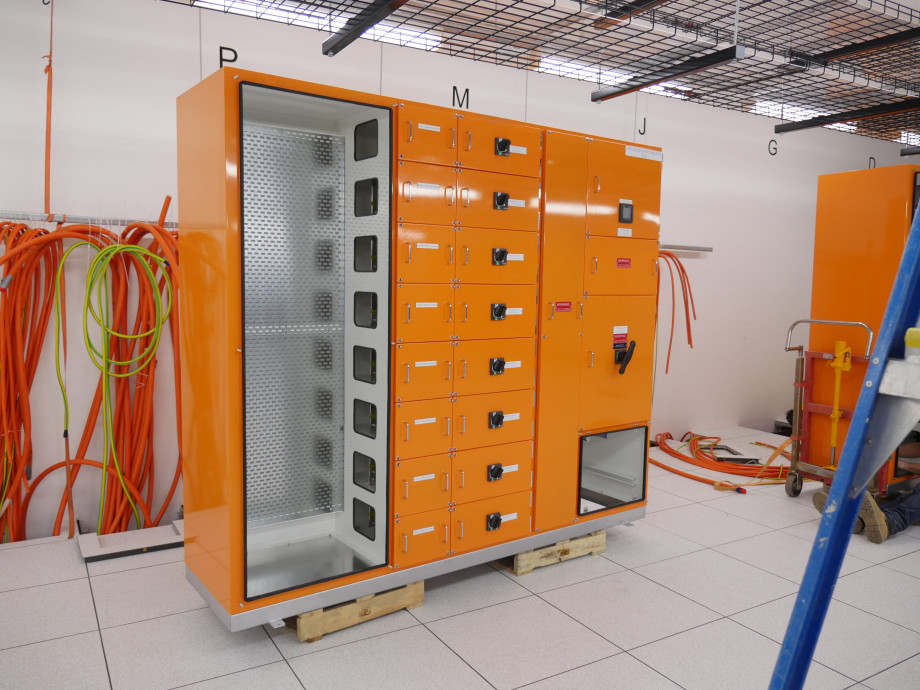 An orange metal box with opened compartments showing where electrical cables will connect.
