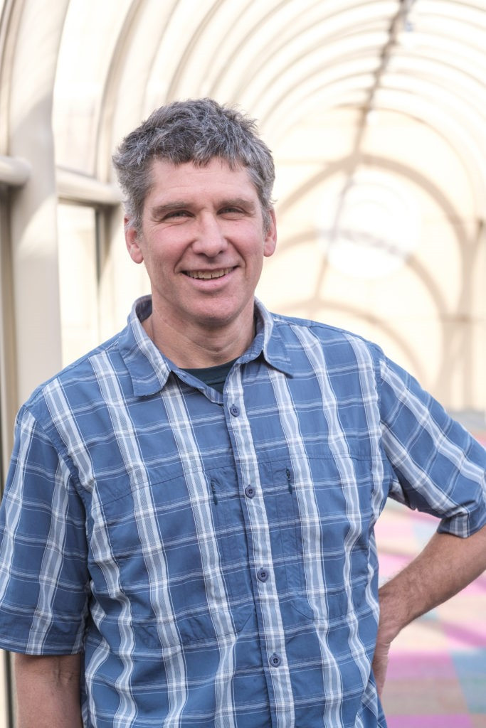 Smiling man in vertical striped shirt looking at the camera.