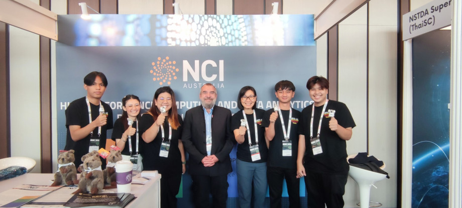 Seven people standing in a conference booth in front of NCI logo, six holding small koalas.