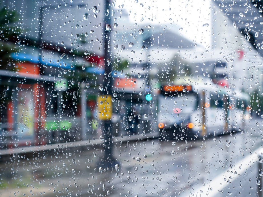 Blurry Melbourne streetscape, including a tram, seen through a rain-soaked window. 