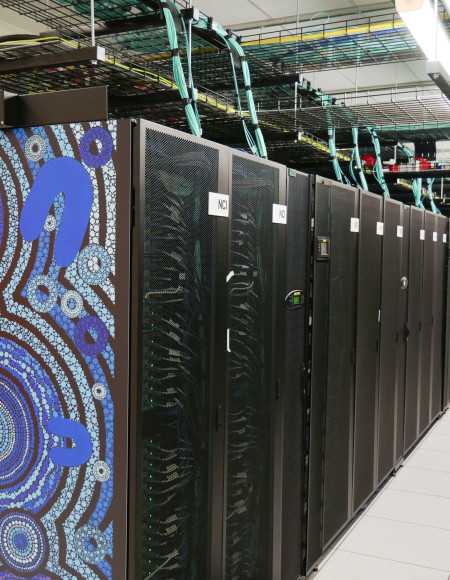 A man holds open a door of the Gadi supercomputer while working on it.