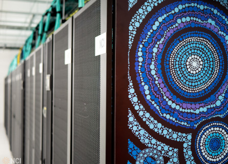 Close-up view of the Gadi artwork with the long row of supercomputer servers visible in the background.