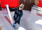 Andrew Smith stands in a hollow in the ice while holding a long cylindrical ice core.