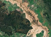 A satellite image of a brown flooded river amongst vivid green bushland in Queensland in 2017.