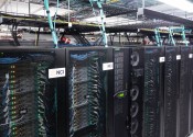 Black mesh cabinets with NCI logos on the front and computer servers, cables and lights visible inside them.