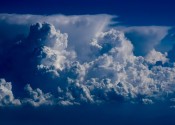 A blue-tinged picture of a large wide storm cloud in the distance.