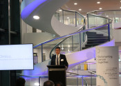 Professor David Thomas presenting on stage in front of an Omico banner in the Garvan Institute of Medical Research.